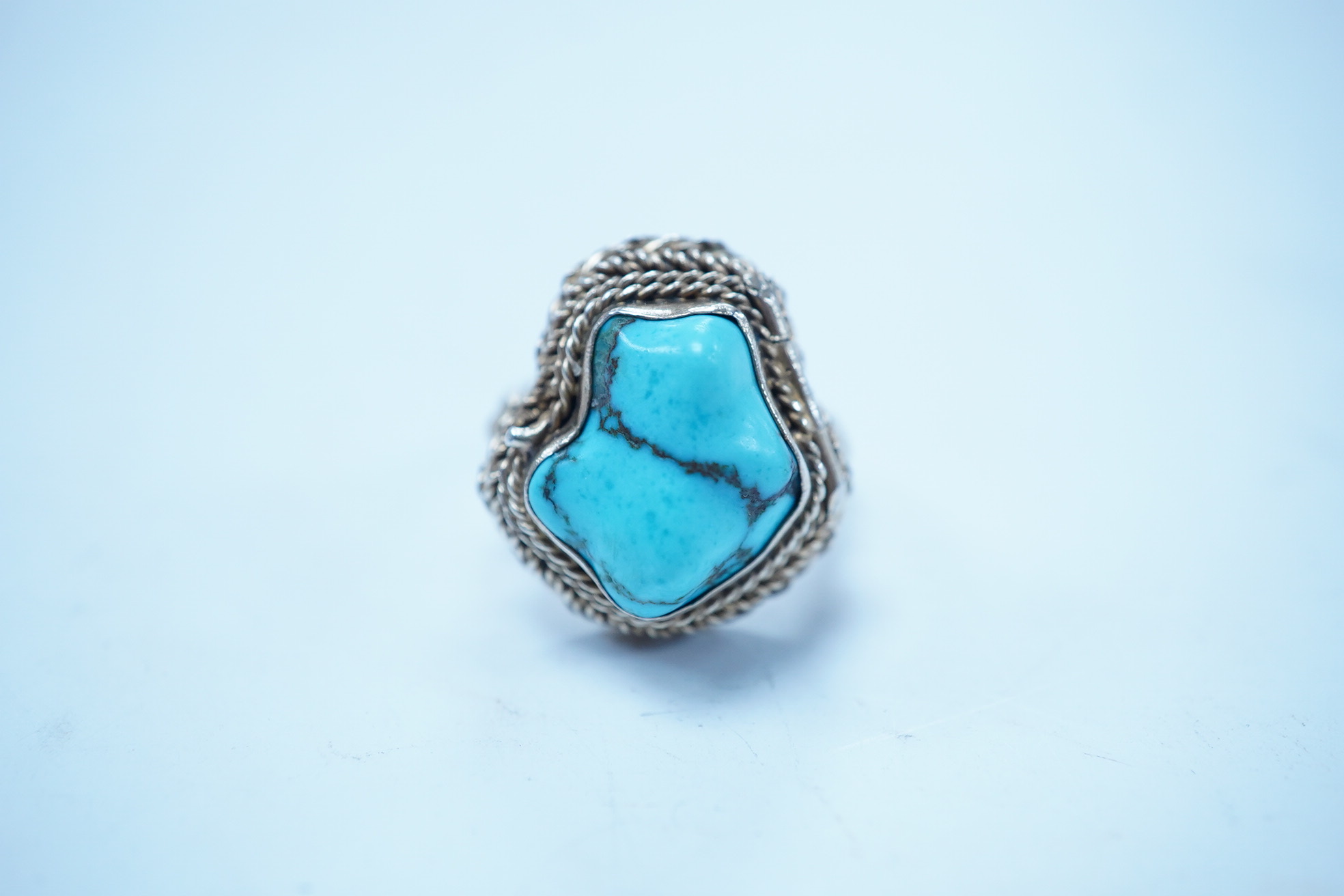 A Chinese gilt white metal and turquoise set 'poison ring' the hinged compartment opening to reveal a carved agate Buddha, size M. Condition - fair